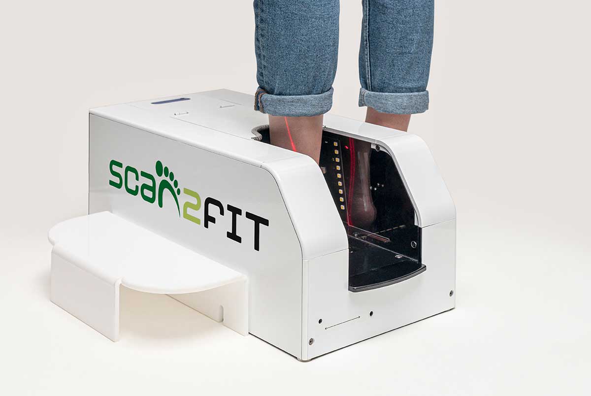 A person using the Scan2Fit machine to measure foot size accurately for shoe fitting.