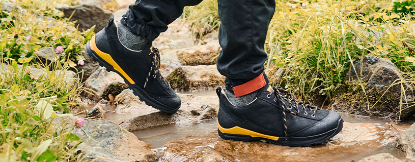 Person wearing waterproof hiking shoes crossing a rocky stream