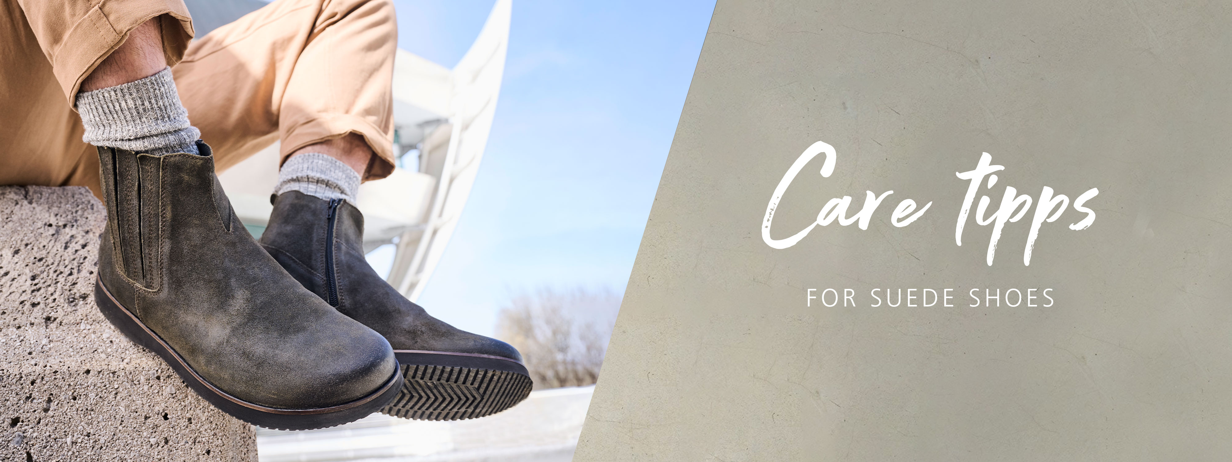 A person wearing stylish suede boots with rolled-up beige pants, sitting on a stone ledge with a modern architectural background, featuring care tips for suede shoes.