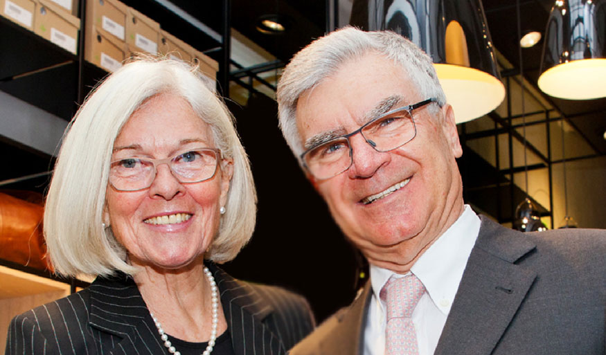 A senior couple in formal attire smiling in a contemporary retail store with shelves and modern lighting
