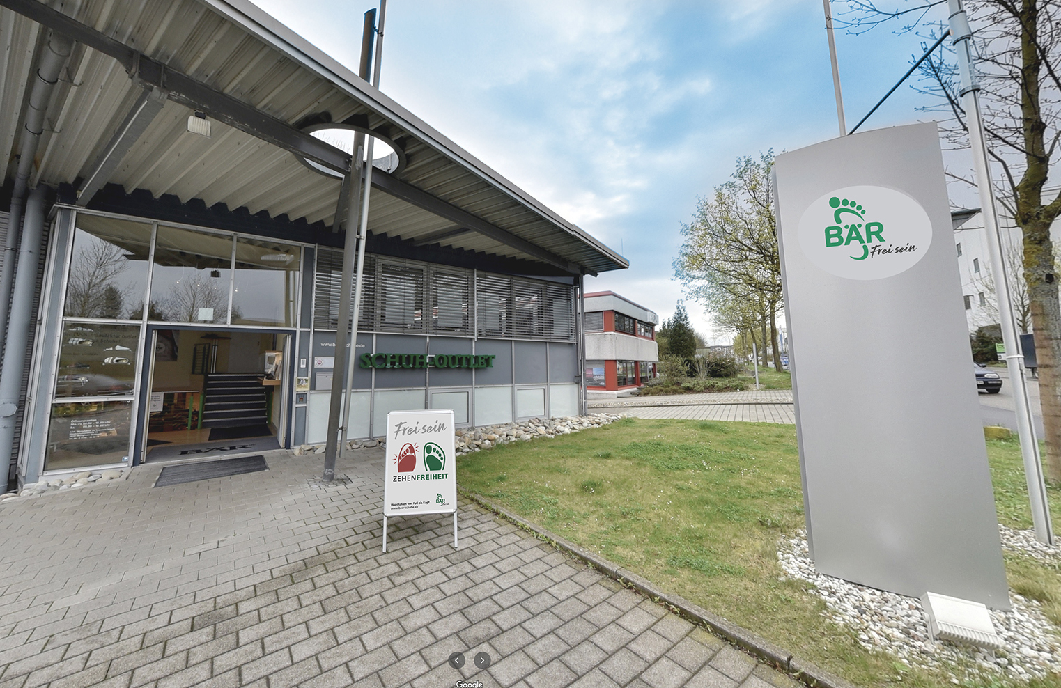 Outdoor view of a shoe outlet store with signage and an entrance pathway