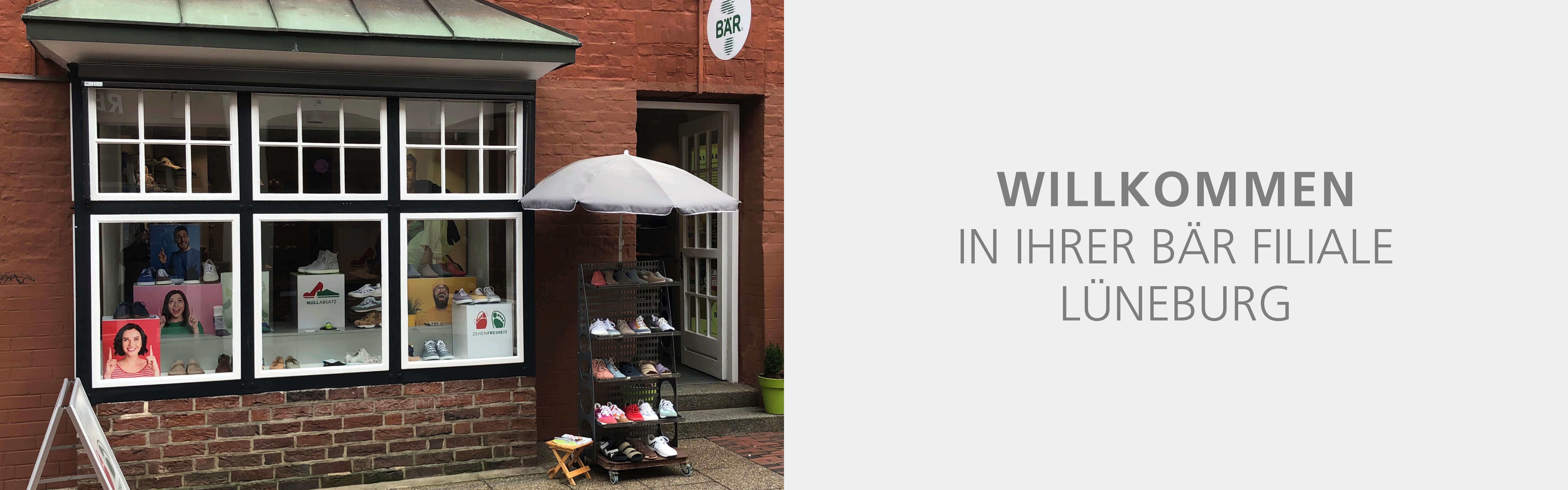 Image of the entrance to a Bär shoe store in Lüneburg with shoes displayed outside and a welcoming sign.